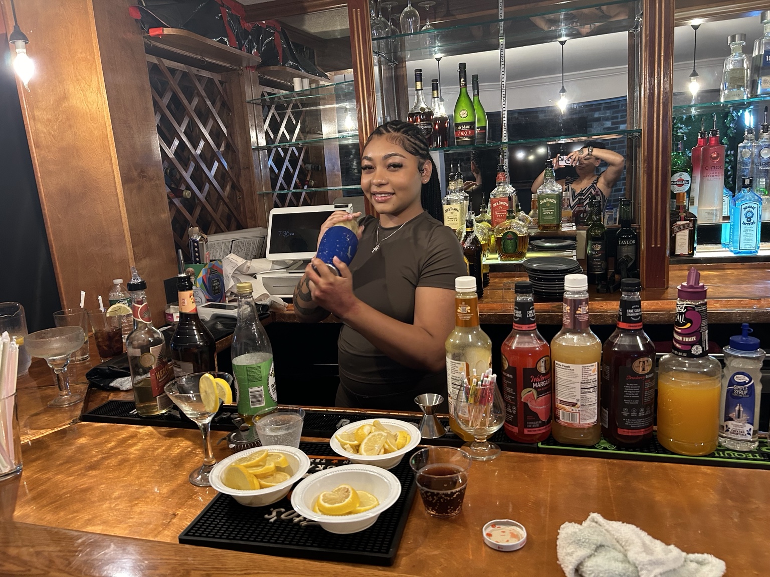Bartender practicing drink preparation behind a working bar