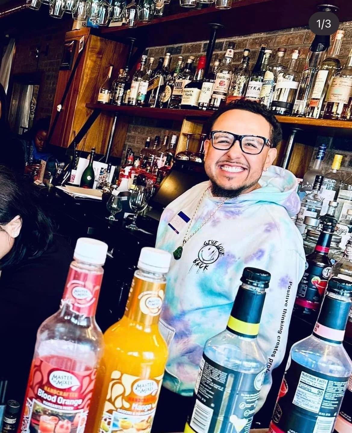 Bartending student smiling behind a working bar